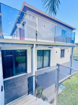 a white house with glass windows and a staircase at Bela Vista Studio in Ponta Delgada