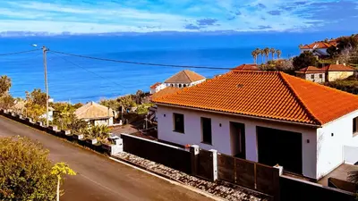 a white house with an orange roof on a street at Bela Vista Studio in Ponta Delgada