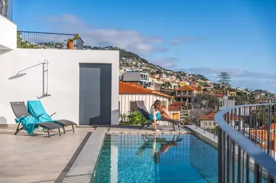 a woman sitting on a chair next to a swimming pool at Atlantic Bloom by Homie in Santa Maria Maior