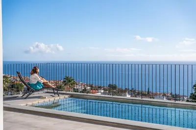 a woman sitting in a chair next to a swimming pool at Atlantic Bloom by Homie in Santa Maria Maior