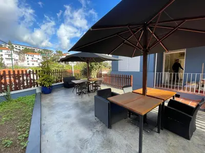 a patio with tables and chairs and an umbrella at Casa do Avô Diogo , By OP in Funchal