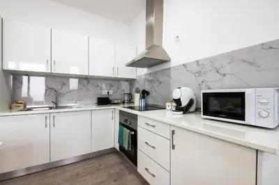 a kitchen with white cabinets and a microwave at Sol Blessing by GALMI in Ponta do Sol