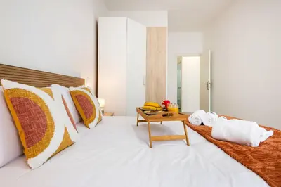a bedroom with a white bed with a wooden table at Sol Blessing by GALMI in Ponta do Sol