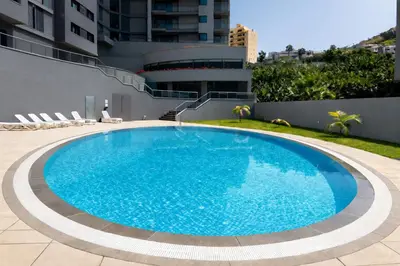 a large blue swimming pool next to a building at Luxury Ocean View Apartment Funchal in Funchal