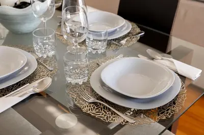 a table with plates and glasses on a glass table at Luxury Ocean View Apartment Funchal in Funchal