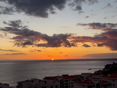 a sunset over the ocean with a city and buildings at Luxury Ocean View Apartment Funchal in Funchal