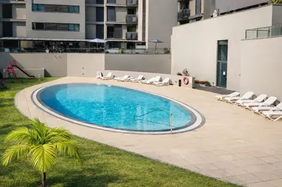 a swimming pool with lounge chairs and a building at Luxury Ocean View Apartment Funchal in Funchal