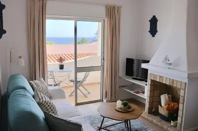 a table and chairs on a balcony with a view of the ocean at Casa Salema Praia Clube in Salema