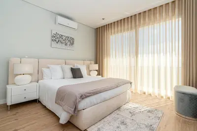 a white bedroom with a large bed and a window at Casa Joaquim by Rent2u, Lda in Arco da Calheta
