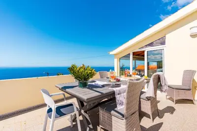 a patio with a table and chairs and the ocean at Casa do Manuel Maria in Estreito da Calheta