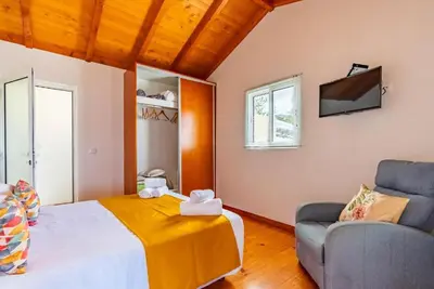 a bedroom with a bed and a couch and a tv at Casa do Manuel Maria in Estreito da Calheta