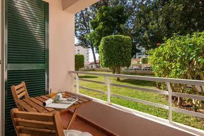 a table and chair on a balcony with a view of a yard at White House I Apartment with Garden View in Funchal
