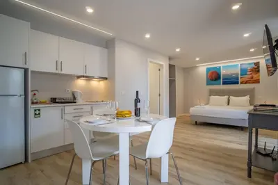 a white kitchen with a white table and chairs at Casa AZUL Apartments in Jardim do Mar