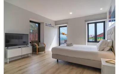 a bedroom with a large bed and a flat screen tv at Casa AZUL Apartments in Jardim do Mar