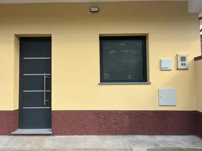 a building with a black door and two windows at Cozy Noia in Machico