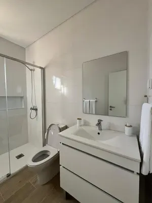 a white bathroom with a toilet and a sink at Cozy Noia in Machico