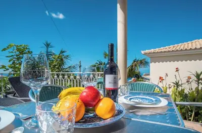 a table with a plate of fruit and a bottle of wine at Villa Boa nova in Funchal