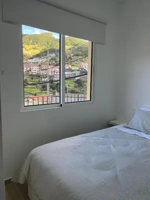 a bedroom with a white bed and a large window at Cozy Noia in Machico
