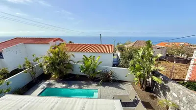 a house with a pool and a table and chairs at Villa Abundância in Arco da Calheta