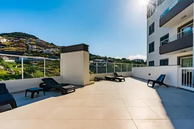 a balcony with chairs and tables on a building at Casa Sol in Caniço