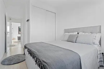 a white bedroom with a large bed and a bathroom at Casa Lobos in Câmara de Lobos