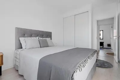 a white bedroom with a large bed with a gray headboard at Casa Lobos in Câmara de Lobos
