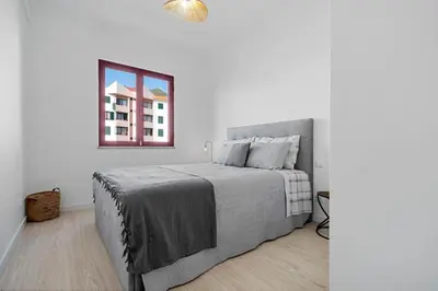 a white bedroom with a bed and a window at Casa Lobos in Câmara de Lobos