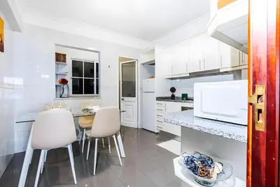 a kitchen with white cabinets and a table and chairs at City Views Apartment Funchal in Funchal