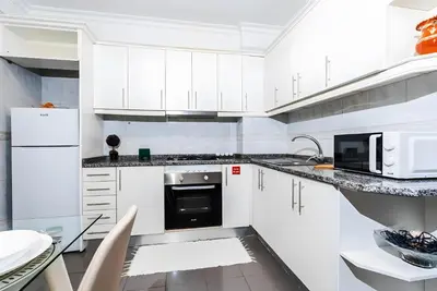 a white kitchen with white cabinets and a black oven at City Views Apartment Funchal in Funchal