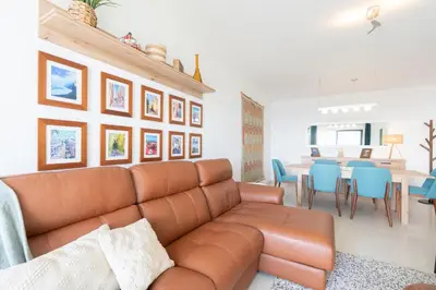 a living room with a brown leather couch and a dining room at Amethyst by LovelyStay in Caniço