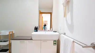 a white bathroom with a sink and a window at Amethyst by LovelyStay in Caniço