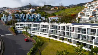 a white building with a car parked in a parking lot at Amethyst by LovelyStay in Caniço