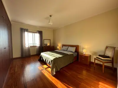 a bedroom with a bed and wooden floors and a window at Forum Madeira pokoje in Funchal
