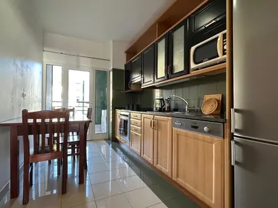 a kitchen with wooden cabinets and a table with a sink at Forum Madeira pokoje in Funchal