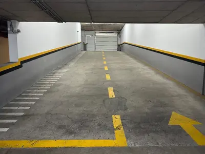 an empty parking garage with a door and yellow arrows at Forum Madeira pokoje in Funchal
