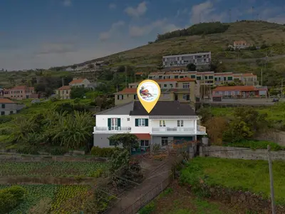a white house with a yellow sign on top of it at Caniço Seaview House in Caniço