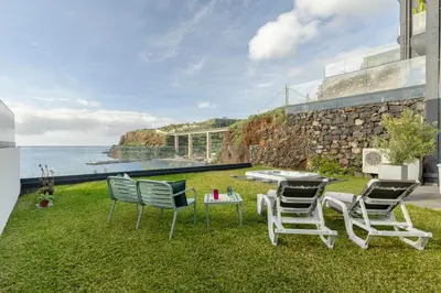 a patio with chairs and a table and the ocean at Luna do Mar - Luxury apt with Jacuzzi in Gaula
