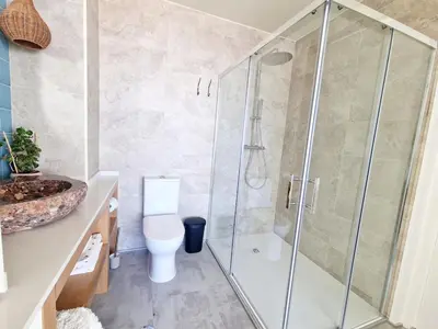 a bathroom with a shower with a toilet and a sink at Romantic Escape - Private jacuzzi and WOW seaview in Lagos