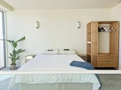 a white bedroom with a bed and a wooden cabinet at Romantic Escape - Private jacuzzi and WOW seaview in Lagos
