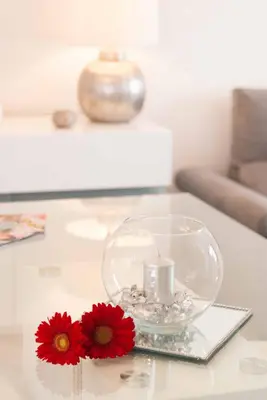 a glass vase with a candle and red flowers on a table at Madeira Sun in Funchal