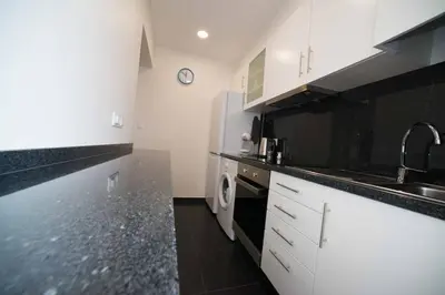 a kitchen with white cabinets and black counter tops at Madeira Sun in Funchal