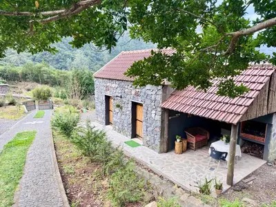 a small stone house with a red roof at Casa do Til in Porto Moniz