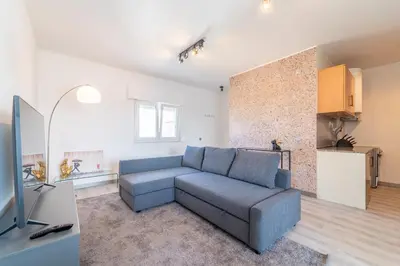a living room with a blue couch and a kitchen at Ocean View Apartment near Arrifana Beach with Parking in Aljezur