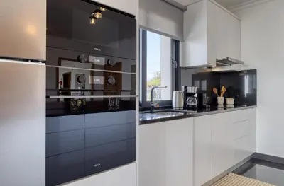 a kitchen with white cabinets and black appliances at Oasis do Sol, a Home in Madeira in Ponta do Sol