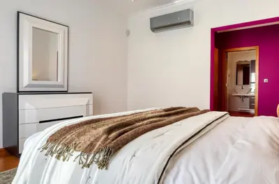 a bedroom with a white bed and a mirror at Oasis do Sol, a Home in Madeira in Ponta do Sol
