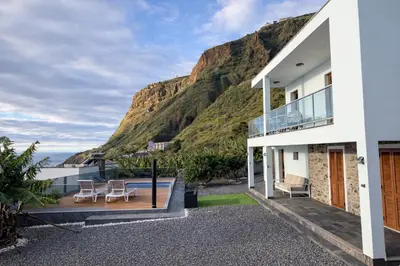a village on a hill next to the ocean at Villa O Pomar with optional heated pool in Paul do Mar