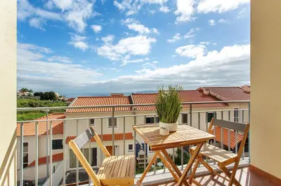 a balcony with a table and chairs and a view of a building at Ti Clara Serenity Apartment in Caniço