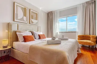 a bedroom with a large bed and a chair at Ti Clara Serenity Apartment in Caniço