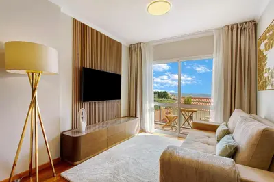 a living room with a couch and a large window at Ti Clara Serenity Apartment in Caniço