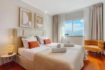a bedroom with a large bed and a chair at Ti Clara Serenity Apartment in Caniço